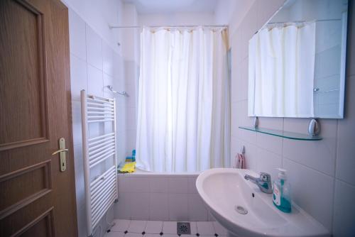 a white bathroom with a sink and a tub at Apartment Kruna Center in Podgorica
