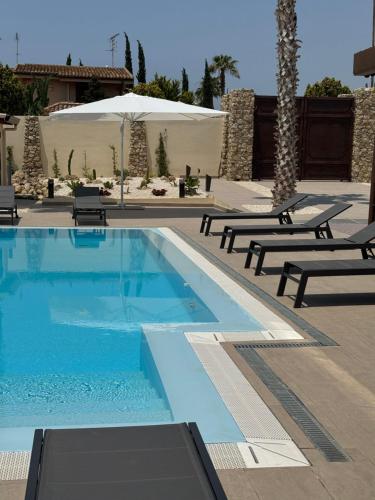 a swimming pool with chaises and benches in a resort at Limonaia Luxury Villa in Porto Empedocle