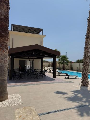 a pavilion with tables and chairs next to a pool at Limonaia Luxury Villa in Porto Empedocle