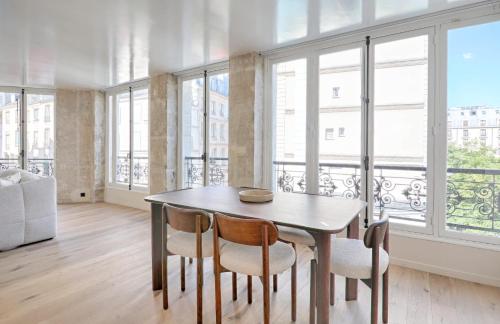 une salle à manger avec une table, des chaises et des fenêtres dans l'établissement Marais Louvre Luxury new 2BR Full AC by Melvane, à Paris
