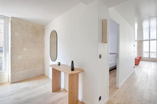 Cette chambre blanche dispose d'une table et d'un miroir. dans l'établissement Marais Louvre Luxury new 2BR Full AC by Melvane, à Paris