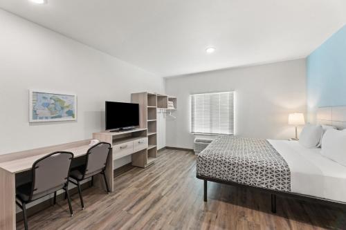 a bedroom with a bed and a desk with a television at WoodSpring Suites Jackson Pearl I-20 in Pearl