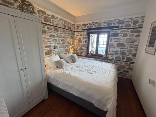 a bed in a room with a stone wall at Villa Olivia in Áyios Vlásios