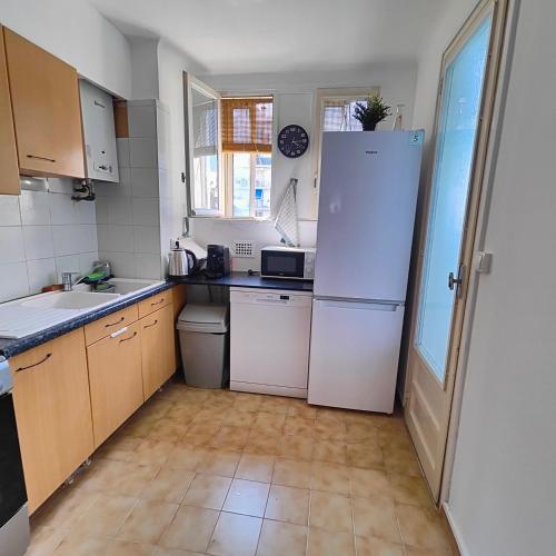 La cuisine est équipée d'appareils électroménagers blancs et d'un grand réfrigérateur. dans l'établissement Appartement Montpellier sud ,F3 calme et reposant, à Montpellier