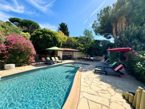 - une piscine avec des chaises et un parasol rouge dans l'établissement Villa Aquavit, à Cavalaire-sur-Mer