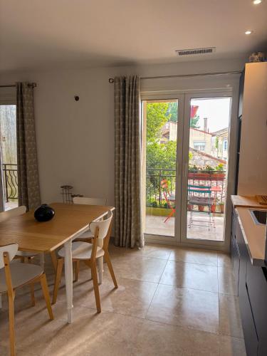 une cuisine et une salle à manger avec une table et un balcon dans l'établissement Maison sol en ciel Petit Dejeuner et Parking inclus, à Aigues-Mortes