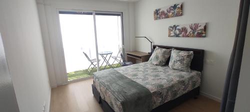 une chambre avec un lit et une grande fenêtre dans l'établissement Le moulin à vent, à Perpignan