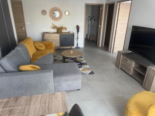 a living room with a couch and a tv at Appartement plage de débarquement-Asnelles in Asnelles
