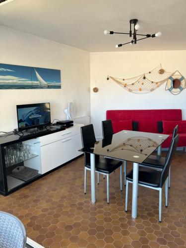 un salon avec une table et un canapé rouge dans l'établissement T2 Les pieds dans l'eau, accès direct plage, à Valras-Plage