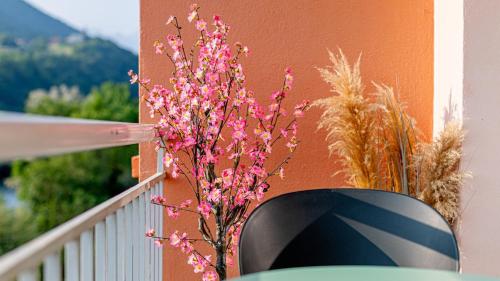 a vase with pink flowers sitting on a balcony at Le Beauregard - Jacuzzi - Garage in Albertville