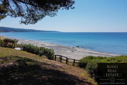 a beach with a fence and the ocean at Casa Calma Beachfront 3bdrm Maisonette in Mola Kalyva