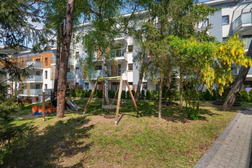 a playground in a park in front of a building at HoliApart in Nautikka Park - blisko plaży, kids club, plac zabaw, garaż podziemny in Krynica Morska