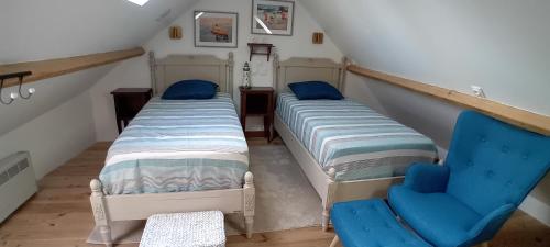deux lits et une chaise bleue dans un grenier dans l'établissement La Goélette Beau duplex A 150 m du centre ville et 400m de la plage de l'écluse, à Dinard