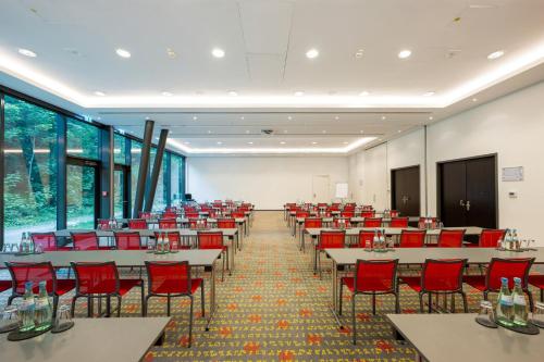 a conference room with tables and red chairs at Holiday Inn Munich - Westpark by IHG in Munich