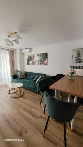 a living room with a green couch and a table at Odiseea Apartment-Private parking included in Sibiu