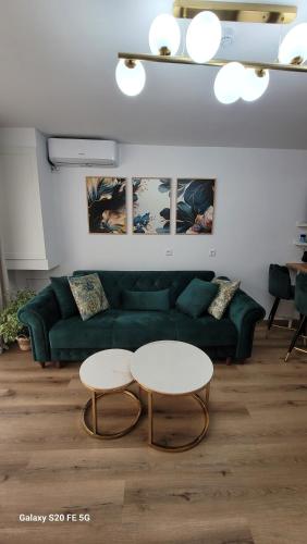 a living room with a green couch and two tables at Odiseea Apartment-Private parking included in Sibiu