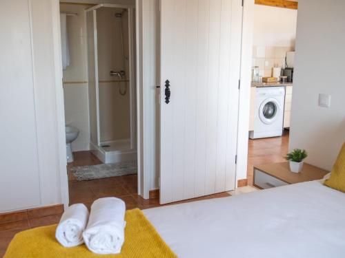 a bedroom with a white bed and a bathroom at Casa Amarela in Zambujeira do Mar