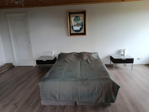 a bed in a white room with two night stands at Kalna Raskumu Apartamenti in Vecpiebalga