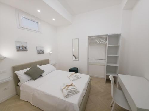 a white bedroom with a bed and a table at Light Charme, Natural Light Apartment a due passi dalla PIAZZA DUOMO in Terrasini