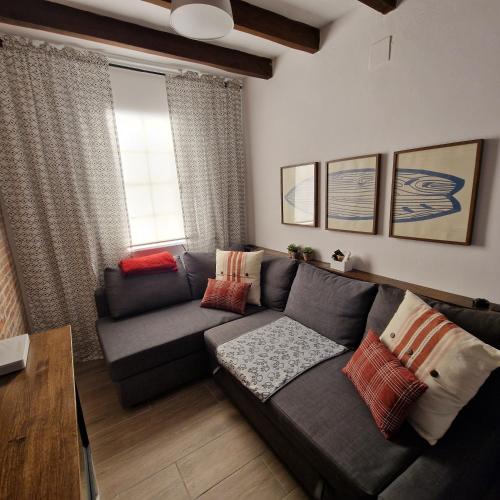 a living room with a gray couch and a window at Casa Los Abuelos in Candeleda