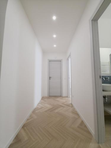 an empty room with white walls and a wooden floor at Light Charme, Natural Light Apartment a due passi dalla PIAZZA DUOMO in Terrasini