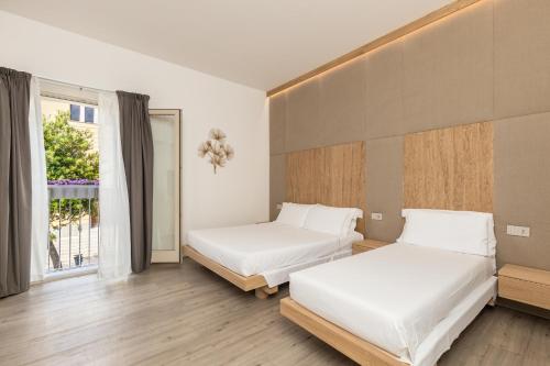 two beds in a room with a window at Aras Hotel Boutique in Villasimius
