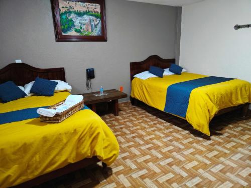 two beds in a room with yellow and blue sheets at Posada Arny in Tepotzotlán