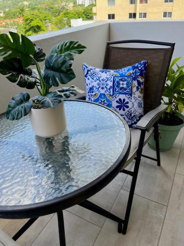 a glass table and chair with a potted plant on a balcony at Millie's Paradise - Bay Beach Ocho Rios in Ocho Rios