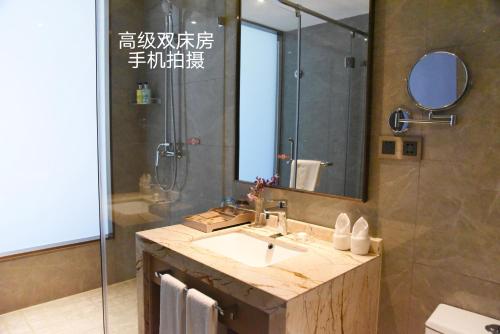 a bathroom with a sink and a shower with a mirror at Nanjing Grand View Hotel in Nanjing