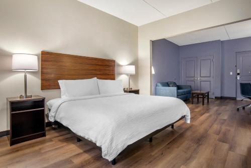 a bedroom with a large white bed and a blue chair at Garner Hotel Panama City Beach Northeast by IHG in Panama City Beach