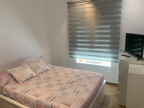 a bedroom with a bed and a window with a television at Apartamento El Atardecer in El Perelló