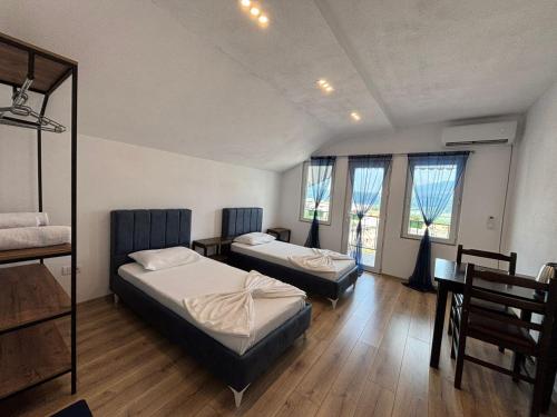two beds in a room with wooden floors and windows at ARBI GUEST House in Kukës