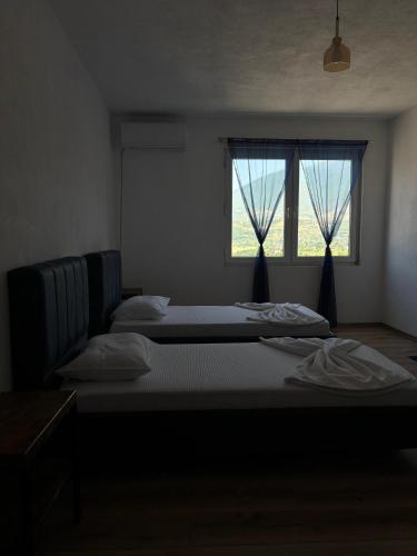 two beds in a room with two windows at ARBI GUEST House in Kukës