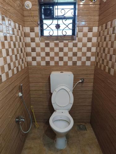 a small bathroom with a toilet and a window at Coconut Inn - Parra Goa in Mapusa
