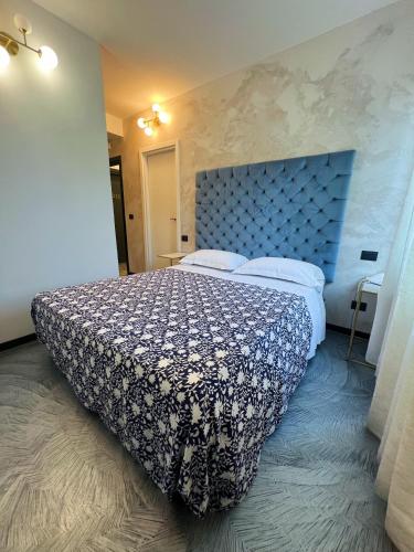 a bedroom with a large bed with a blue headboard at Hotel Le Grazie in Portovenere