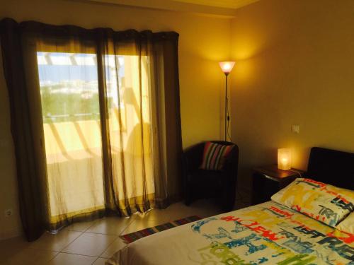 een slaapkamer met een bed en een raam met een stoel bij Albufeira Luxury Villa in Albufeira