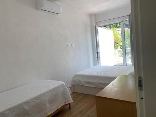 a white bedroom with two beds and a window at Casa Salima a Deiva Marina tra 5 Terre e Portofino in Deiva Marina