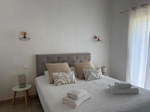 - une chambre blanche avec un grand lit et des serviettes dans l'établissement Mini villa sur Santa Giulia, à Porto-Vecchio