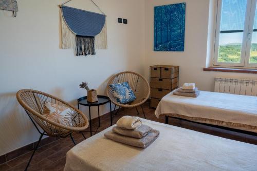 a room with two beds and two chairs and a window at Agriturismo Casa del Vento in San Presto
