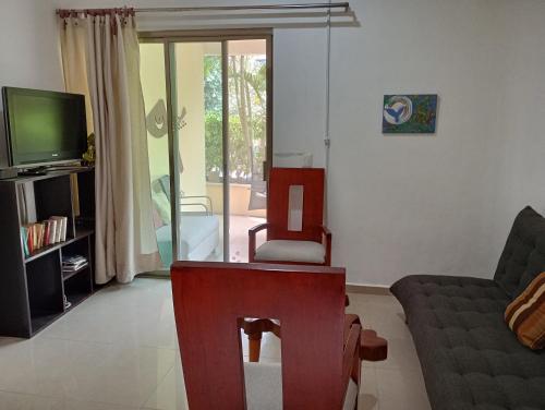 een woonkamer met een bank, een fauteuil en een tv bij Villas Akalan in Tulum