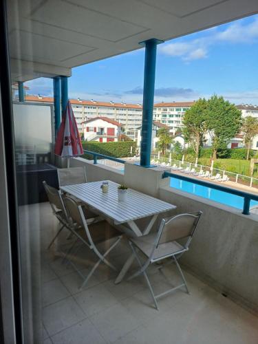 une table et des chaises sur un balcon avec vue sur un immeuble dans l'établissement Appartement du Golf de Ciboure, à Ciboure