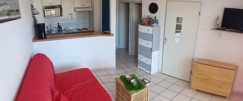 a living room with a red couch and a kitchen at Appartement du Golf de Ciboure in Ciboure
