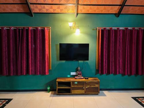 a room with red curtains and a flat screen tv at Rooms For Rent Near Isha ,Kovai Kutrallam in Alāndurai