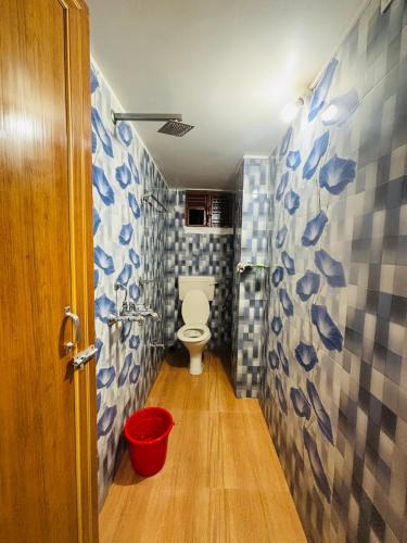 a bathroom with a toilet and a red bucket at Miss Tea Home in Agartala