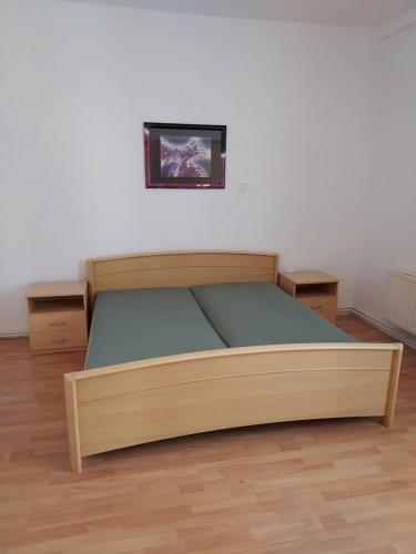 a wooden bed in a room with a picture on the wall at Apartmán v okresu Děčin 