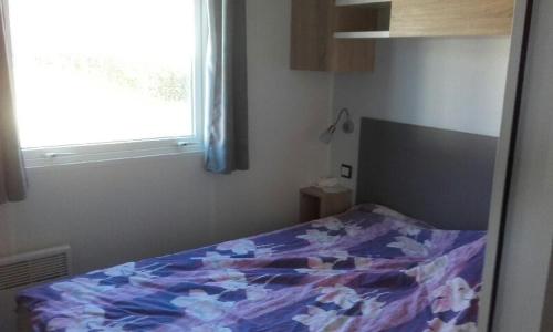 un lit dans une chambre avec une fenêtre dans l'établissement Mobilhome tout confort, à Pont-Aven