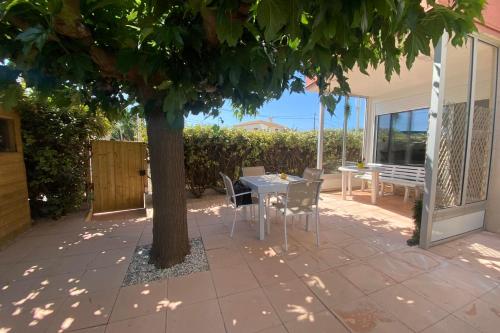 un patio avec une table et des chaises sous un arbre dans l'établissement a garden on the port, à Frontignan