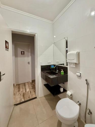 a white bathroom with a toilet and a sink at Puxadinho São Pedro in São Pedro
