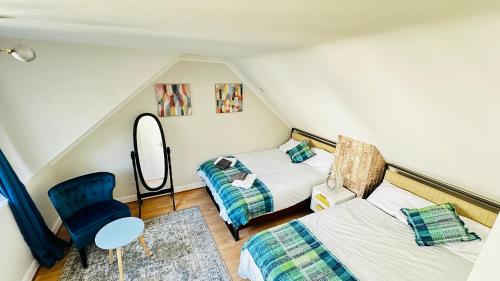 a attic room with two beds and a chair at Inviting 2 Bed Guest House steps away from Ascot Racecourse 3 mins drive, 5 mins to Legoland, 12 mins to Windsor Castle Perfect for families & racegoers alike in Winkfield