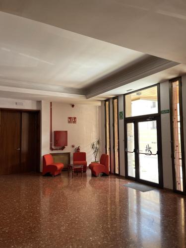 an empty room with red chairs and a television at Albergue Rosa Molas in Arrabal de Jesús